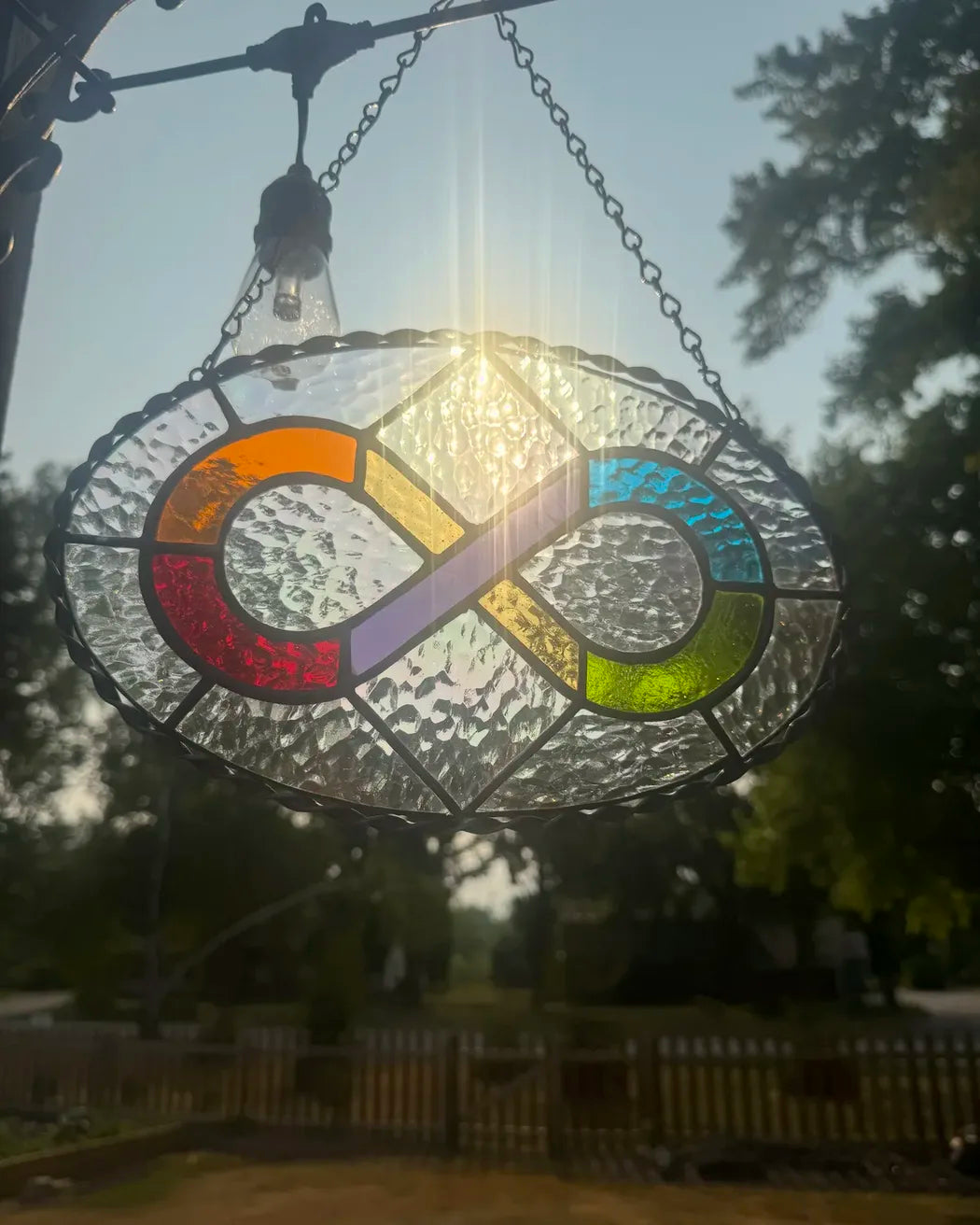 Close-up of iridescent glass and twisted metal border on a rainbow infinity symbol stained-glass suncatcher