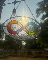 Close-up of iridescent glass and twisted metal border on a rainbow infinity symbol stained-glass suncatcher