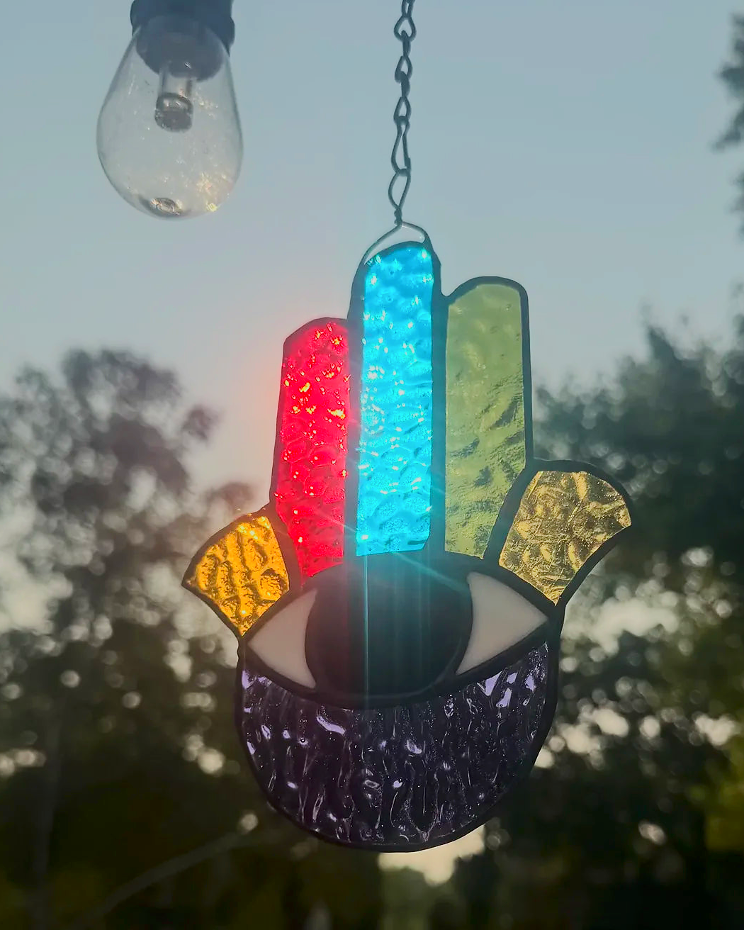 Hand of Fatima stained-glass suncatcher with seven textured chakra colors and an eye in the palm