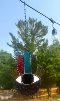 Close-up of the eye and textured chakra-colored glass in the Hand of Fatima stained-glass suncatcher