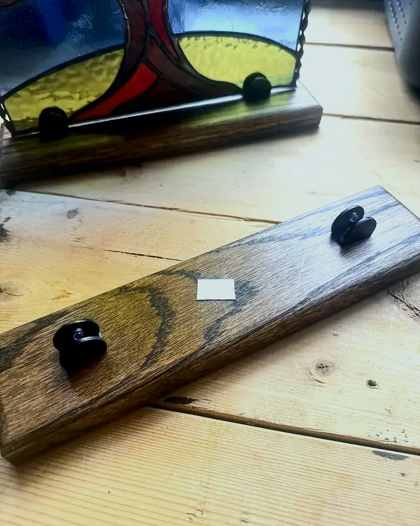 Adjustable Jacobean-stained wood stand with metal clamps holding a stained-glass panel