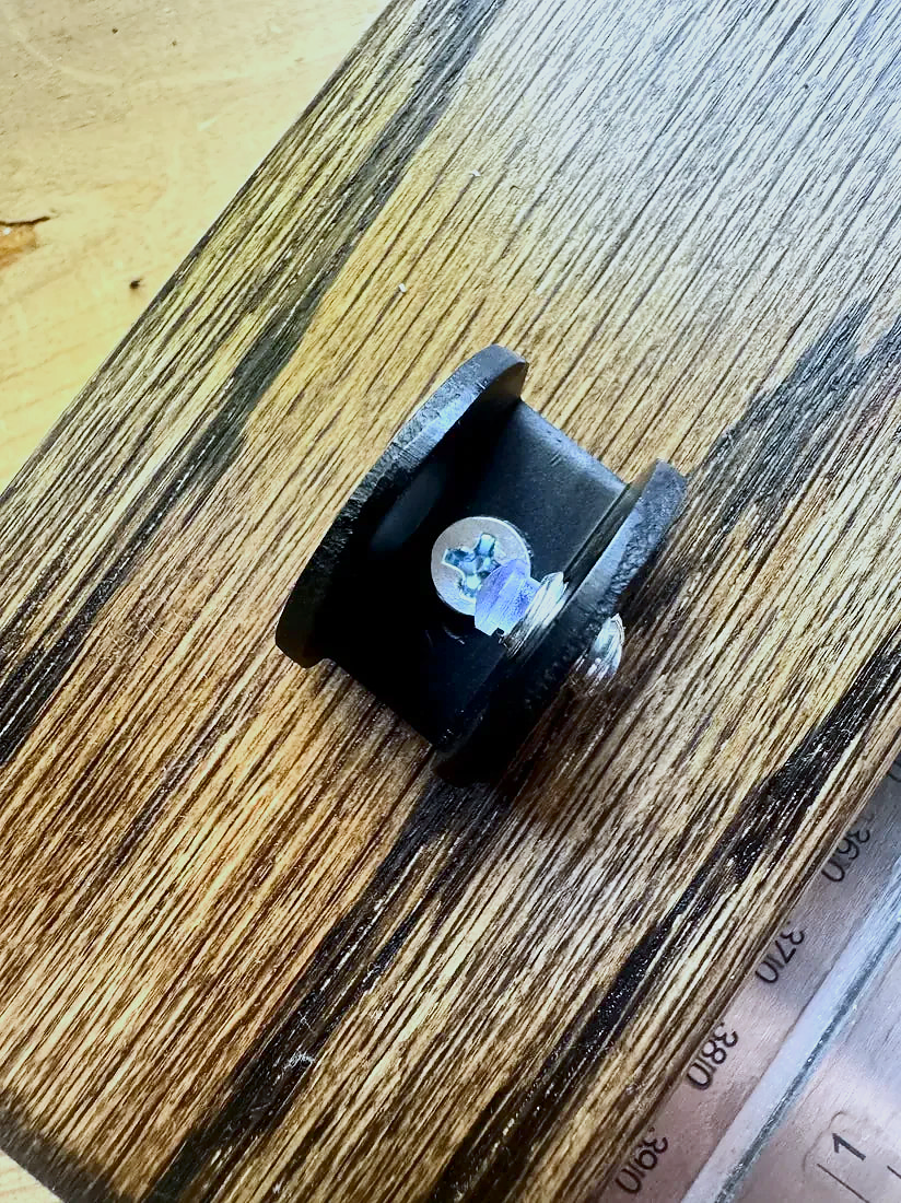 Close-up of the adjustable metal clamp hardware on a Jacobean-stained wood stand