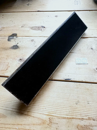 Close-up of the felt-covered base of a Jacobean-stained wood stand
