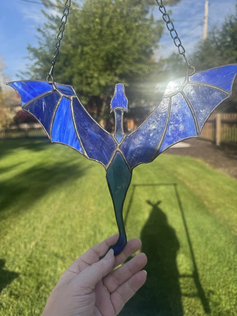 Dragon in Flight stained glass suncatcher in blue, held up in the sun