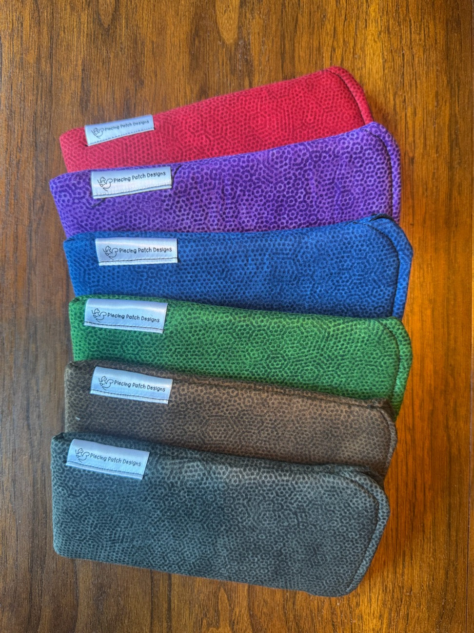 Group of padded solid-color fabric eyeglass cases with built-in lens cloths