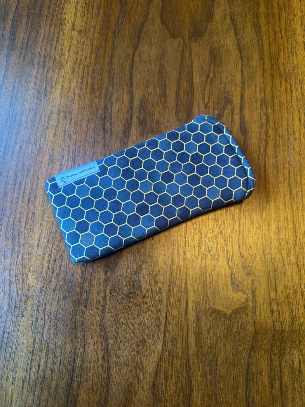 Padded fabric eyeglass case in black, grey, and gold honeycomb metallic print, with built-in lens cloth