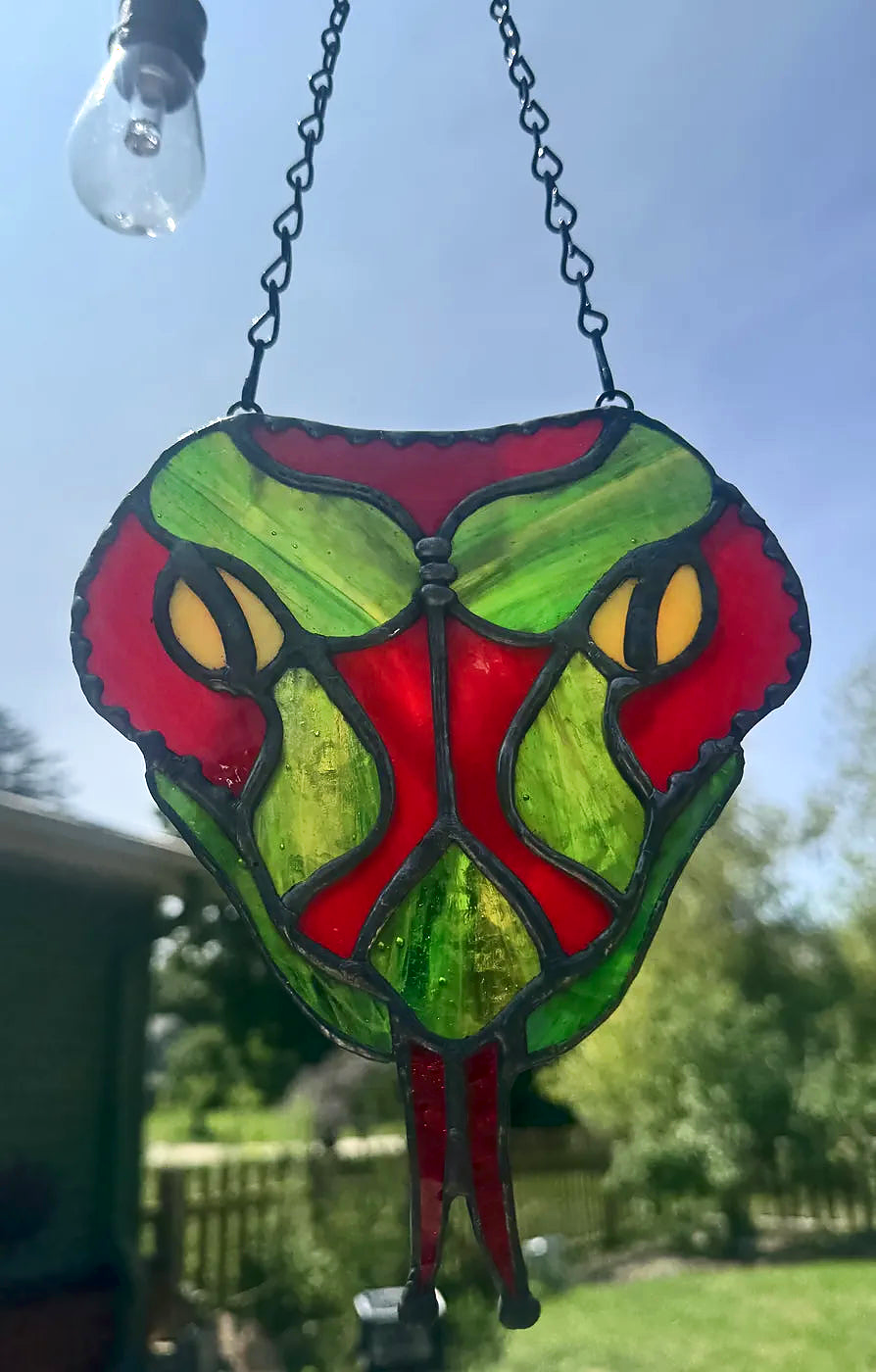 Close-up of the red snake-head stained-glass suncatcher with layered textured glass