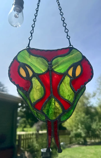 Close-up of the red snake-head stained-glass suncatcher with layered textured glass