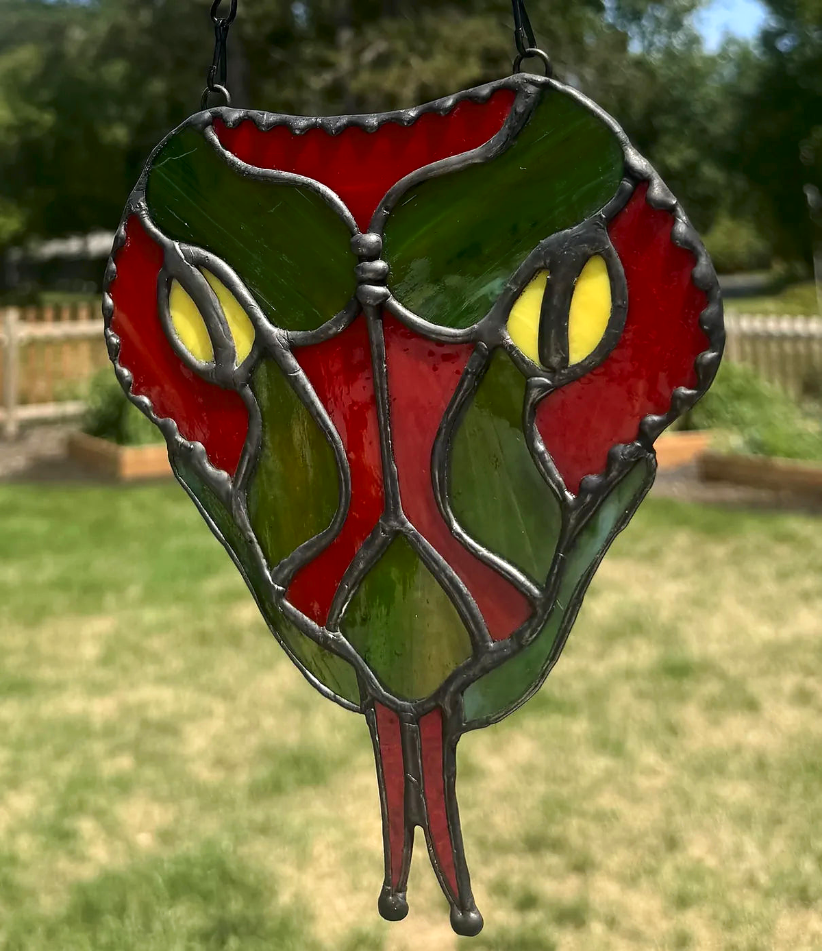 Red snake-head stained-glass suncatcher with yellow eyes and forked red tongue