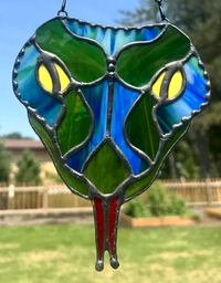 Close-up of the blue snake-head stained-glass suncatcher with layered textured glass