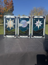 The Sun, The Moon and The Star stained-glass tarot panels displayed together outdoors, showing their iridescent glass and included stands.
