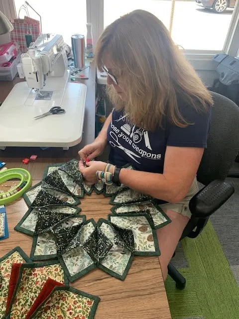 Renee Merwin sewing quilted pieces at her studio table